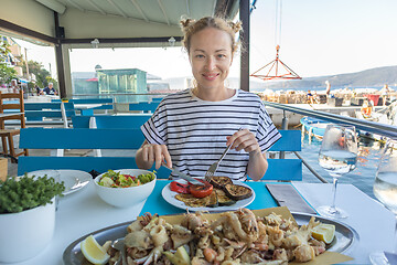 Image showing Beautiful female tourist eating delicious sea food on summer vacation in traditional croatian costal restorant by the sea