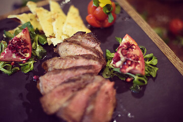 Image showing Juicy slices of grilled steak on wooden board