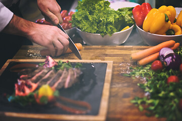 Image showing closeup of Chef hands serving beef steak