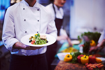 Image showing Chef hands holding dish of fried Salmon fish fillet