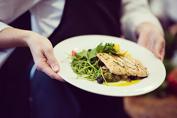 Image showing Chef hands holding dish of fried Salmon fish fillet