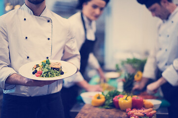 Image showing Chef hands holding dish of fried Salmon fish fillet