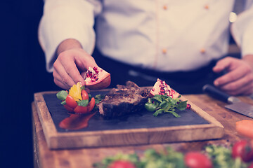 Image showing closeup of Chef hands serving beef steak