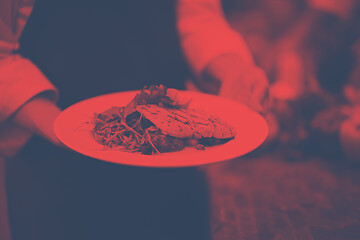 Image showing Chef hands holding dish of fried Salmon fish fillet