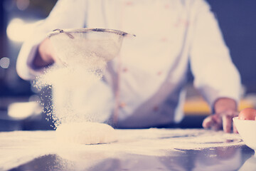 Image showing chef sprinkling flour over fresh pizza dough