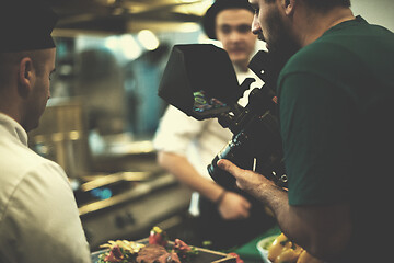 Image showing videographer recording while team cooks and chefs preparing meal