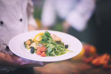 Image showing Chef hands holding dish of fried Salmon fish fillet