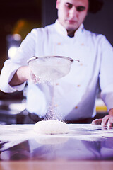 Image showing chef sprinkling flour over fresh pizza dough