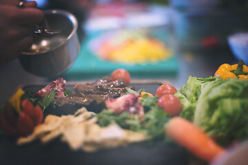 Image showing Chef hand finishing steak meat plate