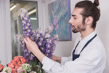 Image showing Small business. Male florist in flower shop. Floral design studio, making decorations and arrangements.