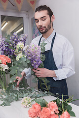 Image showing Small business. Male florist in flower shop. Floral design studio, making decorations and arrangements.