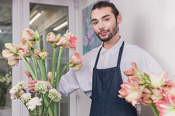 Image showing Small business. Male florist in flower shop. Floral design studio, making decorations and arrangements.
