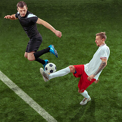 Image showing Football players tackling ball over green grass background