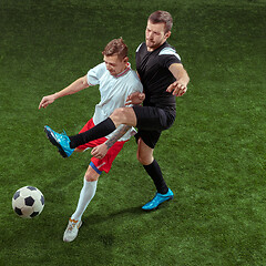 Image showing Football players tackling ball over green grass background