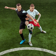 Image showing Football players tackling ball over green grass background