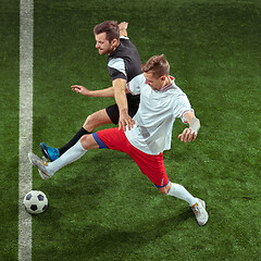 Image showing Football players tackling ball over green grass background