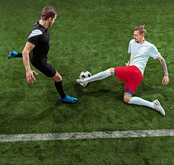 Image showing Football players tackling ball over green grass background