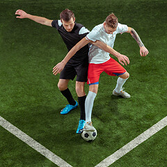 Image showing Football players tackling ball over green grass background