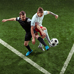 Image showing Football players tackling ball over green grass background