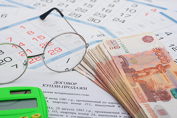 Image showing The purchase agreement contains a bundle of money, a calculator and glasses