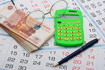 Image showing Money, glasses, calculator and pen lie on the calendar