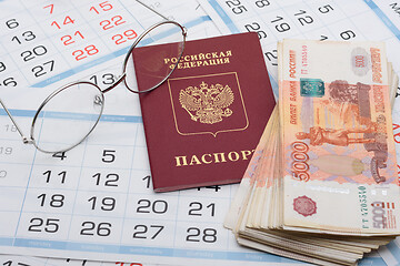 Image showing Glasses, passport and a bundle of money are on the sheets of a wall calendar