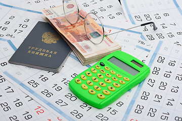 Image showing Labor book, a bundle of money, glasses and a calculator lies on the background from the calendar