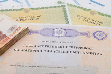 Image showing State certificate for maternity capital, two birth certificates and a bundle of five thousandth bills