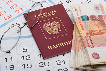 Image showing The passport of the Russian Federation lies on the background of calendar numbers, next to it lies a bundle of money and glasses