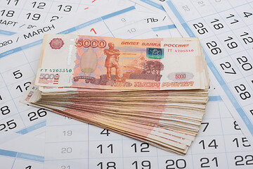 Image showing On the sheets of the calendar are stacks of five thousandth bills