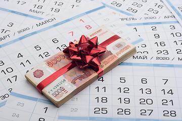 Image showing A bundle of Russian five-thousandth bills with a red bow lies on a background from a calendar