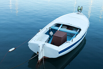 Image showing Vintage old white wooden row boat on blue sea water