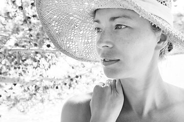 Image showing Close up portrait of no makeup natural beautiful sensual woman wearing straw sun hat on the beach in shade of a pine tree in black and white.