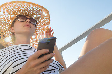 Image showing Beautiful, romantic blonde woman on summer vacations traveling by cruse ship ferry boat holding and using mobile phone. Summer vacation lifestyle