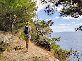 Image showing Young active feamle tourist wearing small backpack walking on co