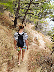 Image showing Young active feamle tourist wearing small backpack walking on co