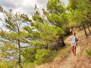 Image showing Young active feamle tourist wearing small backpack walking on co