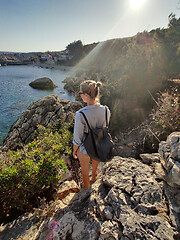 Image showing Young active feamle tourist wearing small backpack walking on coastal path among pine trees enjoing beautiful costal view of Velo Zarace beach on Hvar island, Croatia. Travel and adventure concept