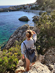 Image showing Young active feamle tourist wearing small backpack walking on coastal path among pine trees enjoing beautiful costal view of Velo Zarace beach on Hvar island, Croatia. Travel and adventure concept