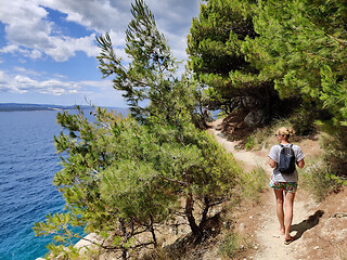 Image showing Young active feamle tourist wearing small backpack walking on co