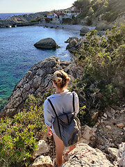 Image showing Young active feamle tourist wearing small backpack walking on coastal path among pine trees enjoing beautiful costal view of Velo Zarace beach on Hvar island, Croatia. Travel and adventure concept