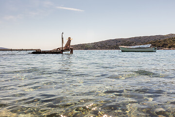 Image showing View of unrecognizable woman wearing big summer sun hat tanning topless and relaxing on old wooden pier in remote calm cove of Adriatic sea, Croatia