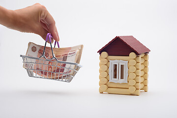 Image showing A hand brings a basket with a bundle of Russian five-thousandth bills to the house