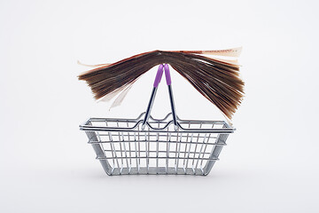 Image showing A large stack of paper bills is on the handles of a grocery basket, front view