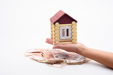 Image showing A hand holds a house over a bundle of Russian five-thousandth bills