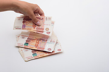 Image showing Hand throws 5000 rubles banknotes on a white background