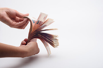 Image showing Hand fan counts a wad of money, white background