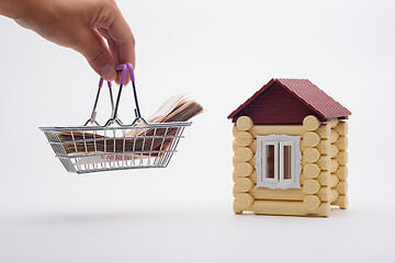 Image showing A hand brings a basket with a wad of money to the house