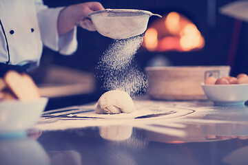 Image showing chef sprinkling flour over fresh pizza dough