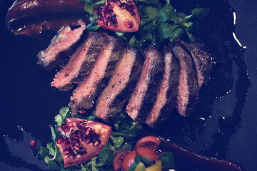 Image showing Juicy slices of grilled steak on wooden board